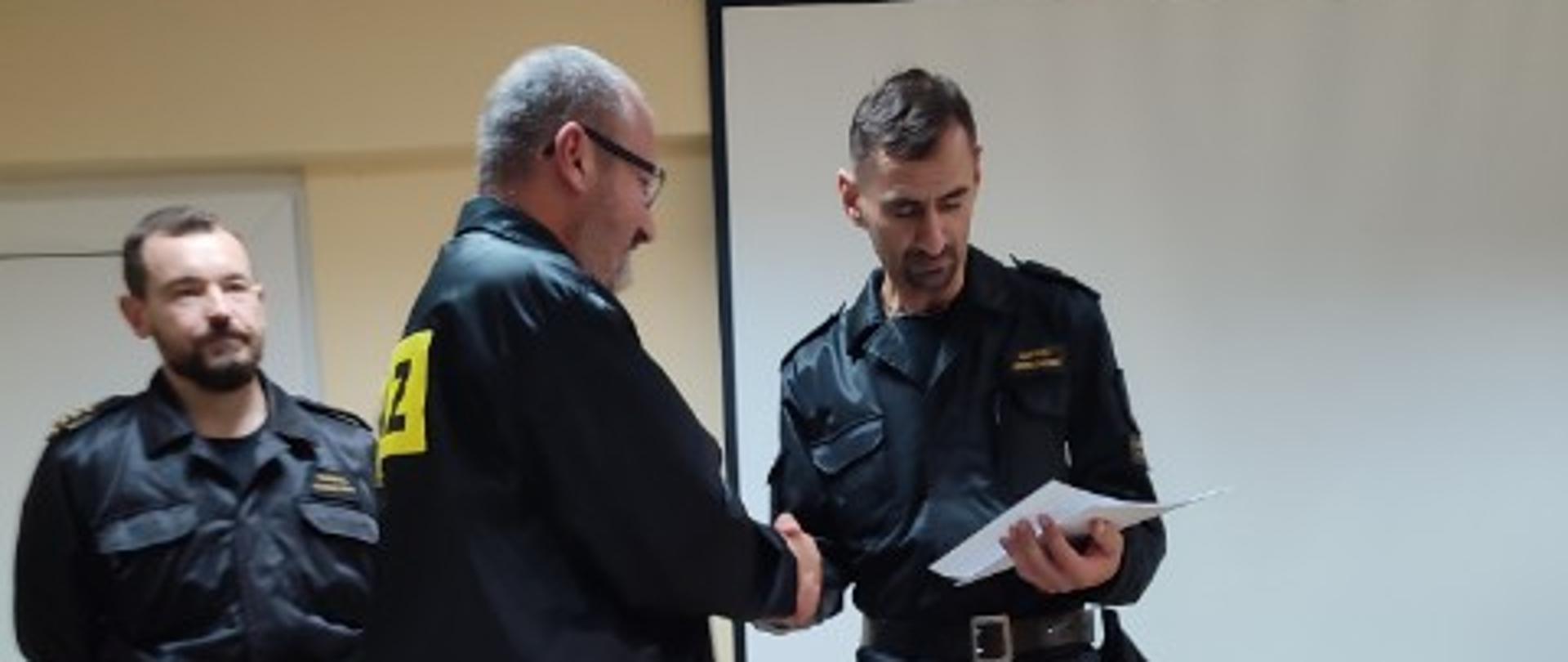 Zdjęcie przedstawia moment wręczenia świadectwa ukończenia szkolenia dla kierujących działaniami ratowniczymi druhowi OSP