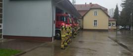 Strażacy przed budynkiem JRG, w tle pojazdy.