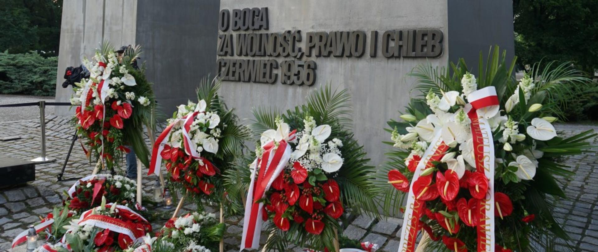 pomnik z napisem o boga za wolność, prawo i chleb czerwiec 1956, przed pomnikiem wiązanki kwiatów
