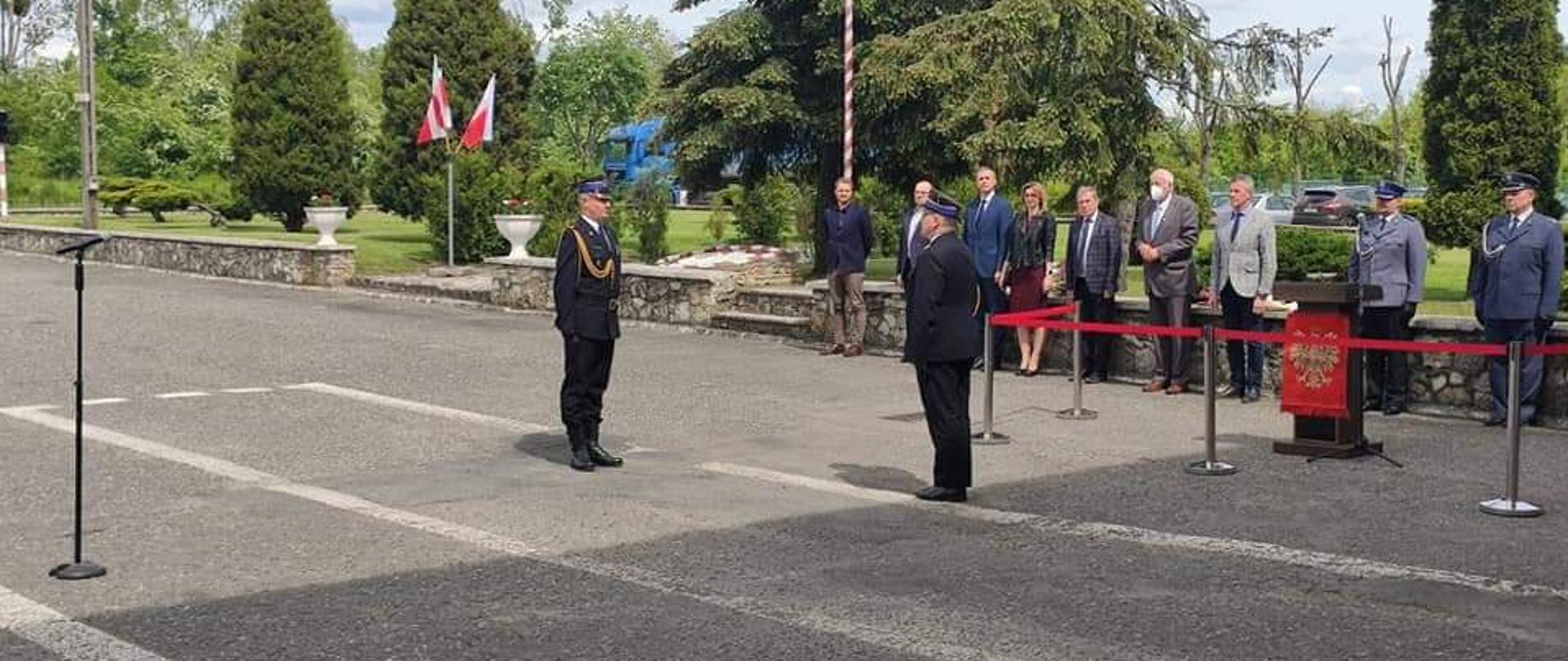 Zdjęcie przedstawia strażaków zgromadzonych podczas apelu na placu przed komendą straży