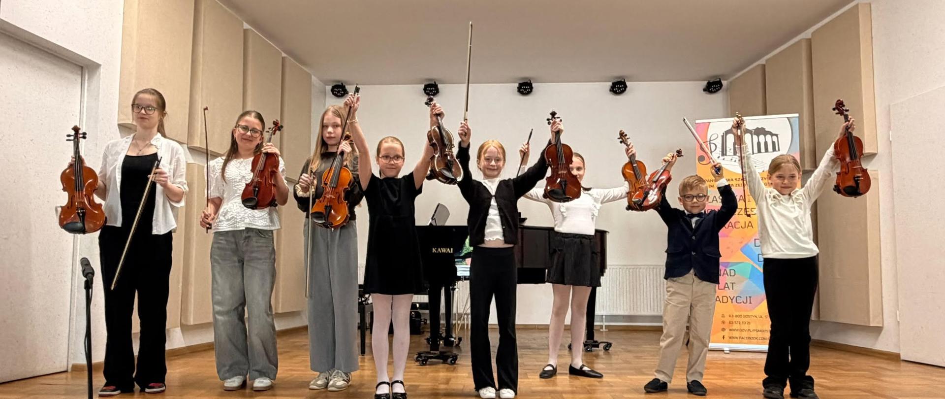 Na scenie stoją uczniowie i trzymają instrumenty. 
