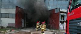 Fotografia przedstawia strażaków podczas pożaru hali produkcyjnej łodzi.