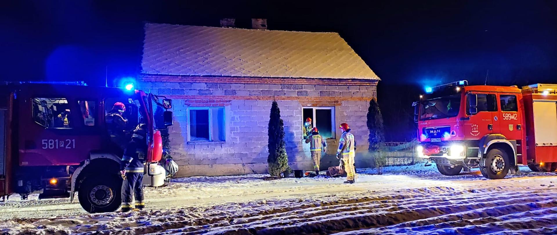 dwa wozy strażackie prze domem w którym wybuchł pożar.