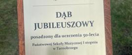 Zdjęcie przedstawia tablicę drzewa posadzonego z okazji Jubileuszu 50-lecia szkoły. 