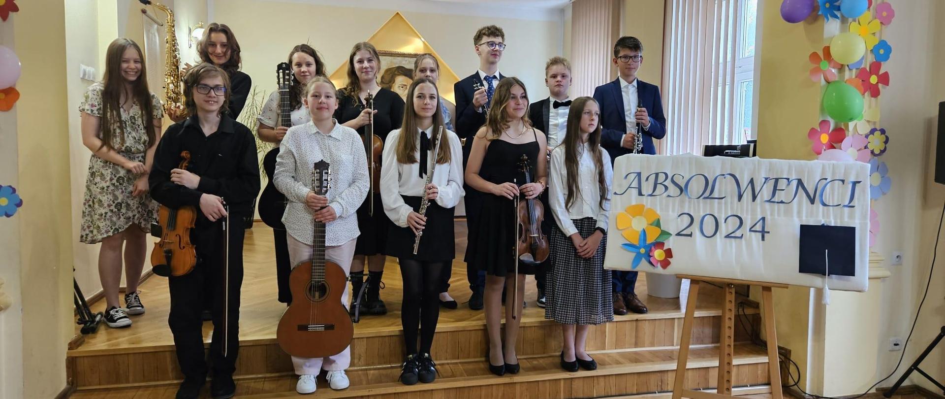 Galeria 14 zdjęć z koncertu absolwentów, który odbył się 19 czerwca 2024 r. Uczniowie grają na różnych instrumentach w auli PSM w Kłodzku.