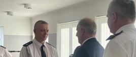 Przedstawiciel ochotniczej straży pożarnej wita się z wojewodą pomorskim za nim stoi pomorski komendant wojewódzki Państwowej Straży Pożarnej.