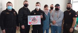 Zdjęcie przedstawia funkcjonariuszy KP PSP w Gołdapi oraz druhów OSP gm. Banie Mazurskie z plakatem akcji krwiodawstwa