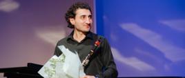 Klarnecista Avetik Ghazaryan stojący na scenie z bukietem kwiatów
