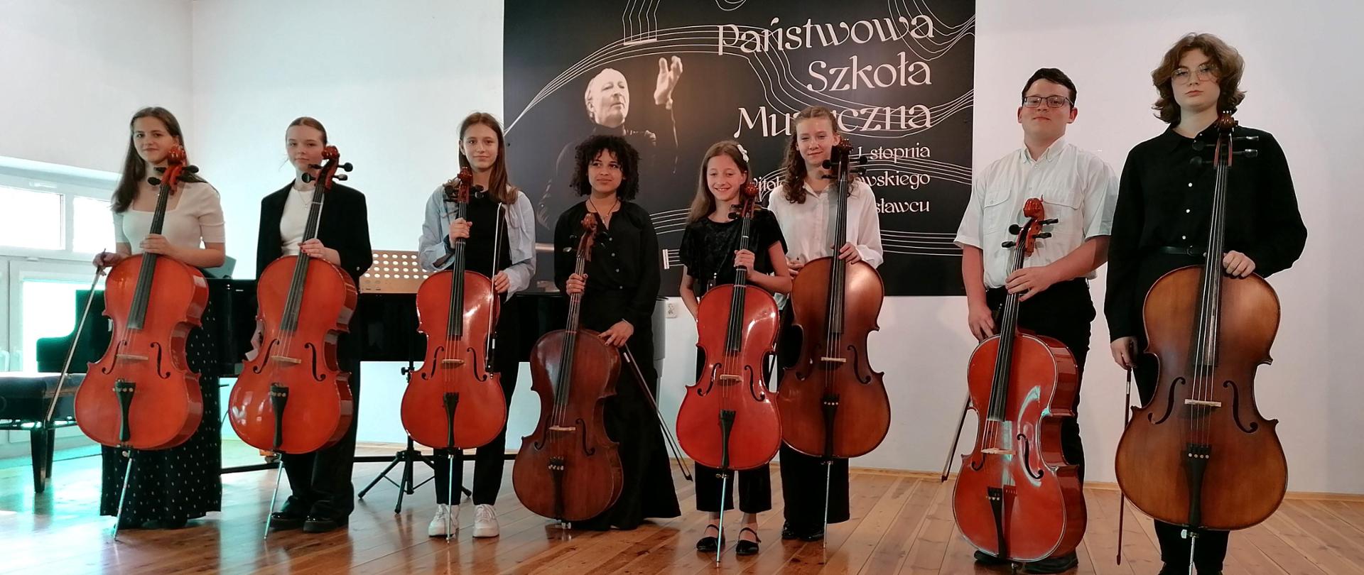 Zdjęcie grupowe przedstawiające wszystkich wykonawców popisu klasy wiolonczeli Doroty Straburzyńskiej, który odbył się 23 maja 2024 r. w auli szkoły.