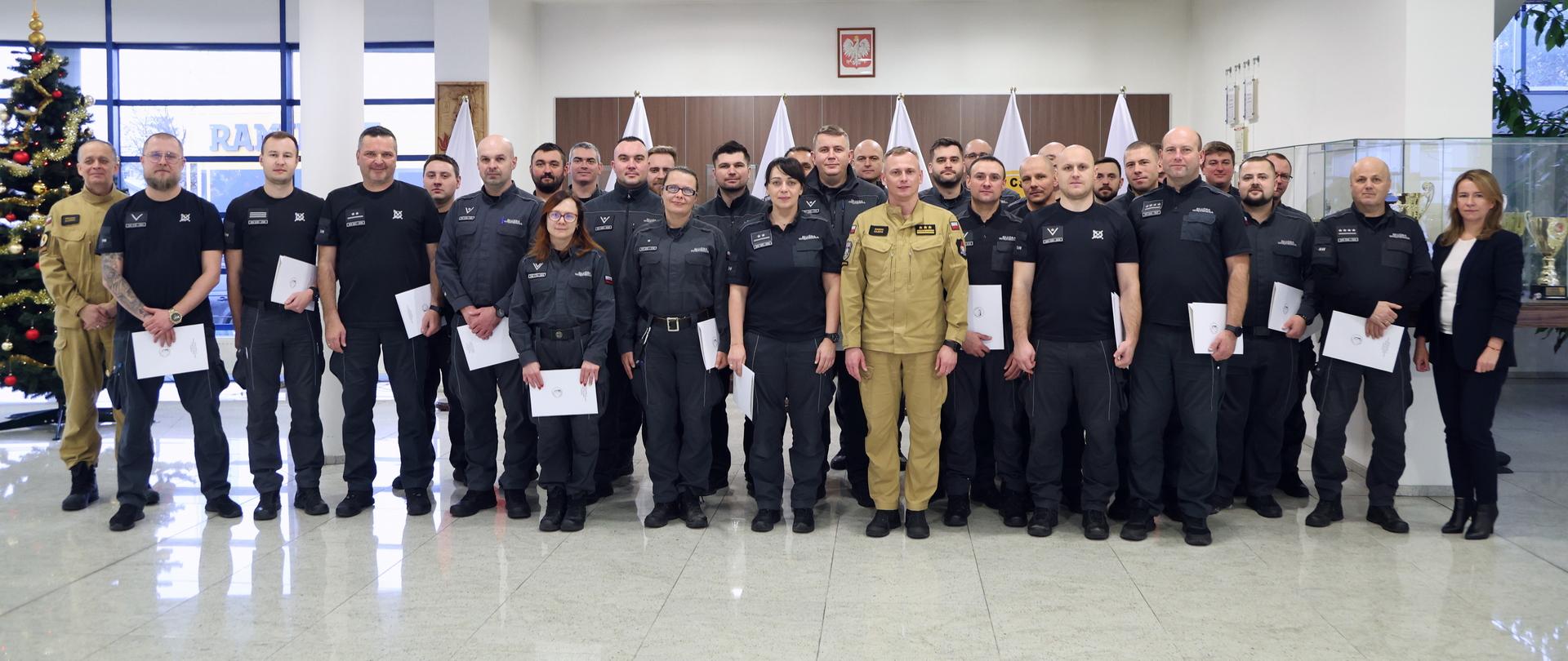 Grupowe zdjęcie funkcjonariuszy służby więziennej (30 osób) w towarzystwie Zastępcy Komendanta Centralnej Szkoły PSP, funkcjonariusza CS PSP oraz kobiety