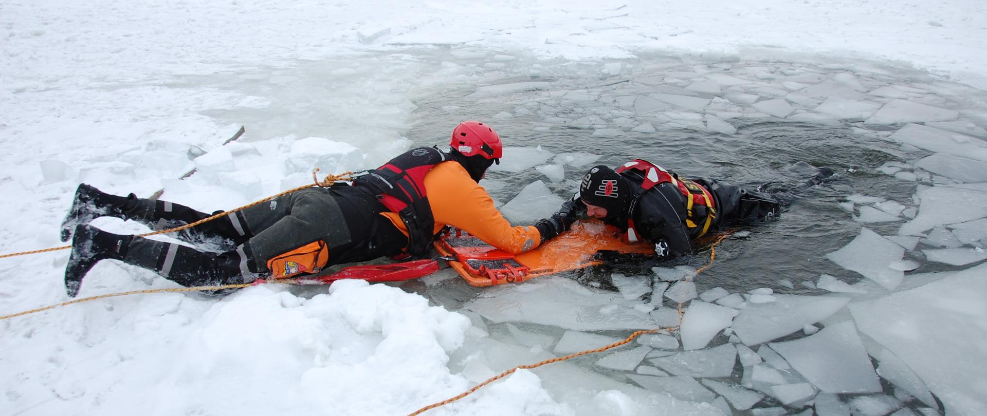 Ratownik wydobywający poszkodowanego z przerębla na taflę lodu