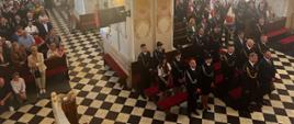 strażacy i inni uczestnicy stoją w kościele podczas mszy świętej