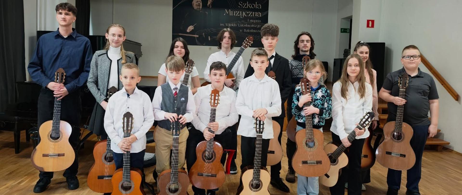 Zdjęcie przedstawiające wykonawców popisu klasy gitary mgr Bartłomieja Filipowicza i mgr Sebastiana Środy, który odbył się 31 marca 2026 r. w auli szkoły.