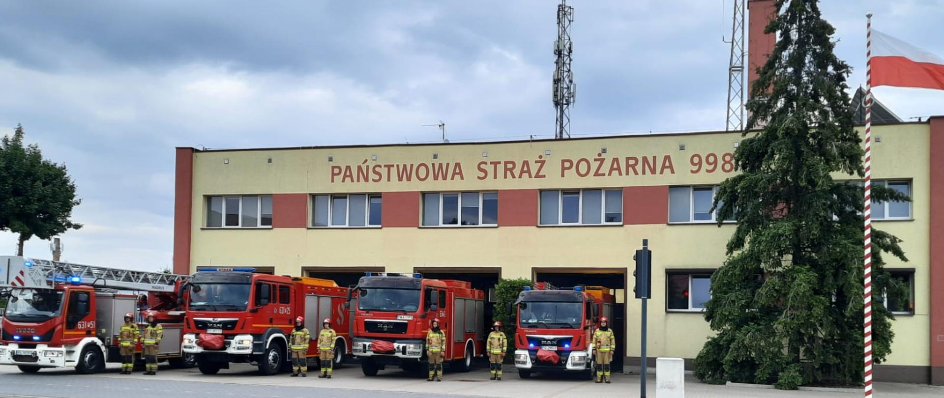 Na zdjęciu widać strażaków na tle wozów strażackich podczas uroczystej zbiórki z okazji rocznicy wybuchu Powstania Warszawskiego 