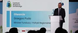 Minister funduszy i polityki regionalnej Grzegorz Puda na konferencji Centrum Wsparcia Doradczego Plus w Katowicach, minister stoi przy mównicy, za jego plecami baner CWD 