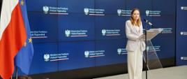 Minister funduszy i polityki regionalnej Katarzyna Pełczyńska-Nałęcz stoi przy mównicy i przemawia do mikrofonu. Po jej prawej stronie flagi Polski i UE, za jej plecami granatowy baner z logotypami MFiPR