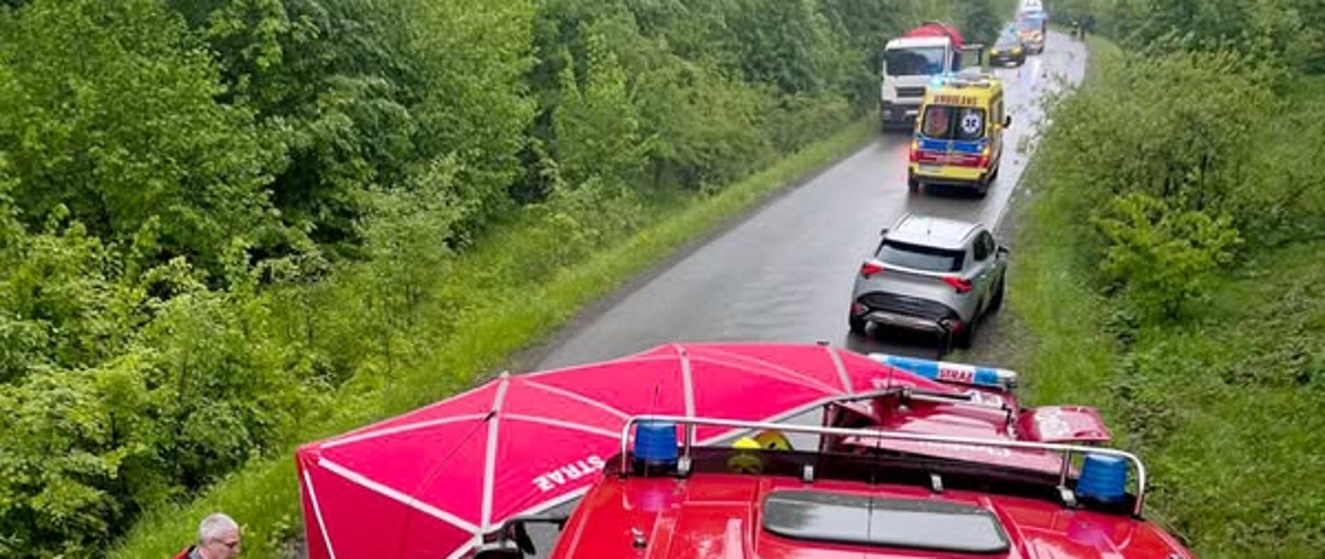 Zdjęcie przedstawia miejsce w wypadku gdzie rozłożony jest parawan, widać ratownika medycznego oraz samochody osobowe i karetkę. Zdjęcie wykonane zostało z dachu samochodu gaśniczego. 