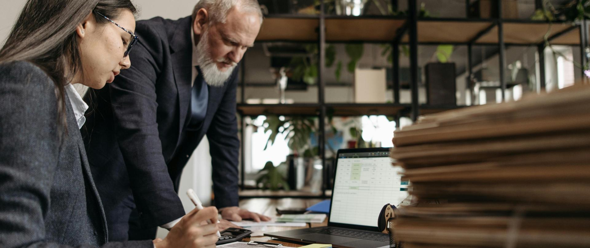 Kobieta i mężczyzna przy biurku, obok laptop i dokumenty