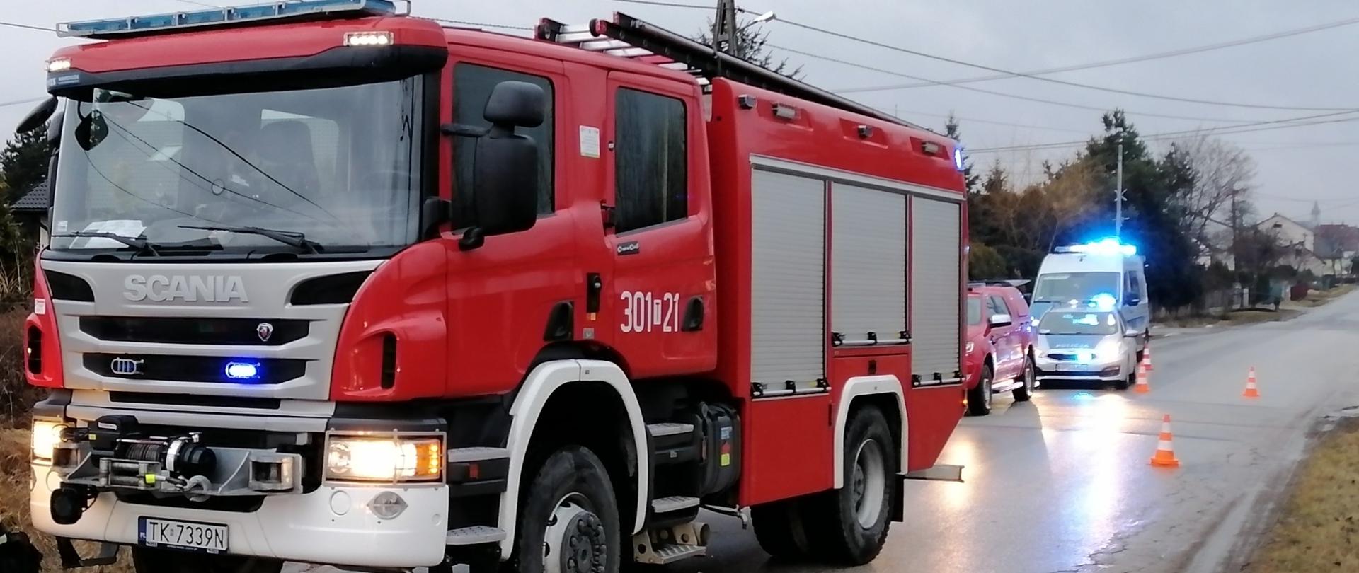 Na zdjęciu przedstawiono ustawione wzdłuż drogi samochody służb ratowniczych biorących udział w akcji. Widać kolejno dwa samochody straży pożarnej oraz dwa radiowozy policyjne.