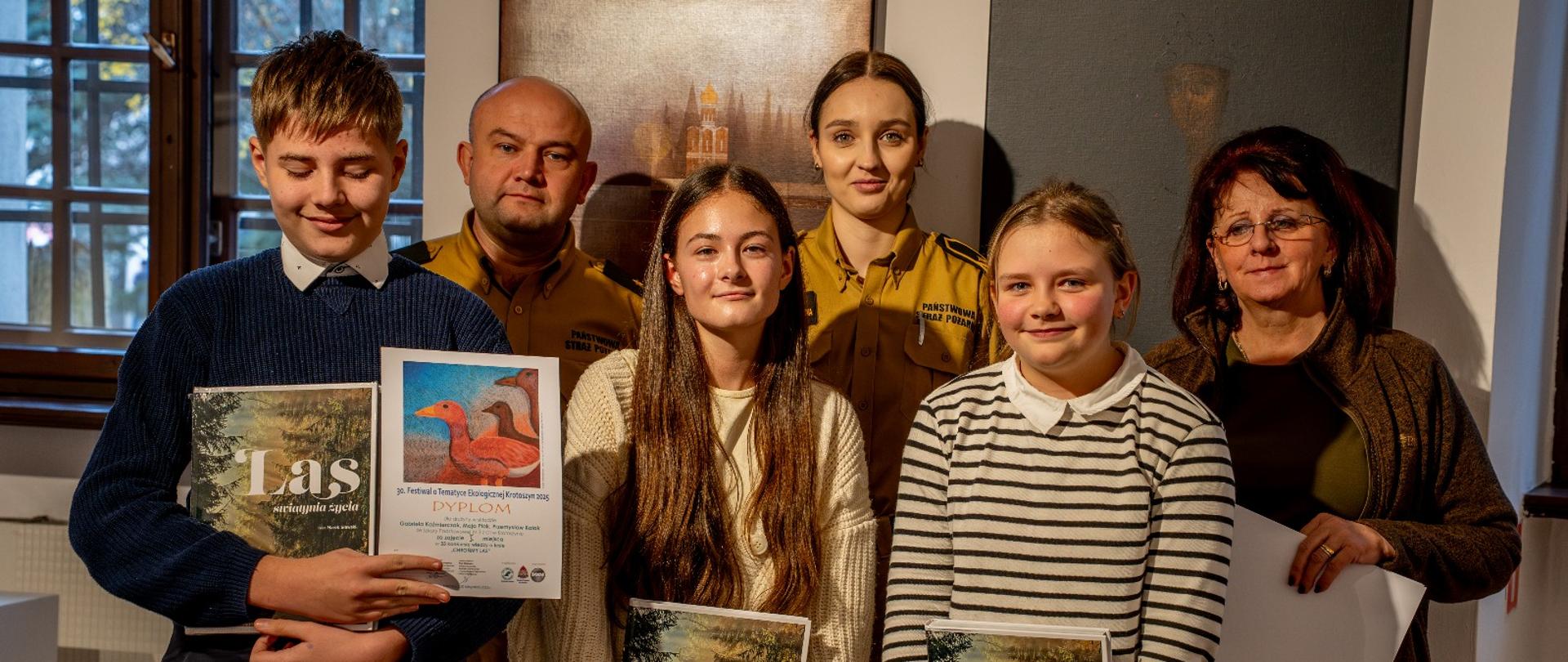 Zdjęcie przedstawia laureatów konkursu trzymających nagrody oraz komisję konkursową.