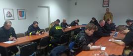 Na zdjęciu widać druhów OSP, którzy piszą egzamin teoretyczny z zakresu pożarnictwa w pomieszczeniu komendy.