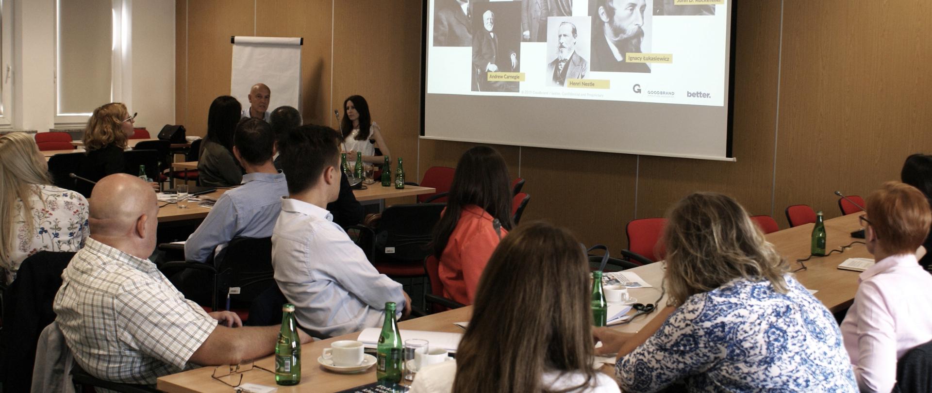 uczestnicy warsztatów patrzą w stronę tablicy z prezentacją