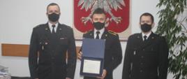 Zdjęcie przedstawia komendanta powiatowego PSP w Kole podczas przekazania podziękowań Ministra Spraw Wewnętrznych i Administracji dla strażaka za akcję ratowniczo-gaśniczą prowadzoną poza granicami kraju