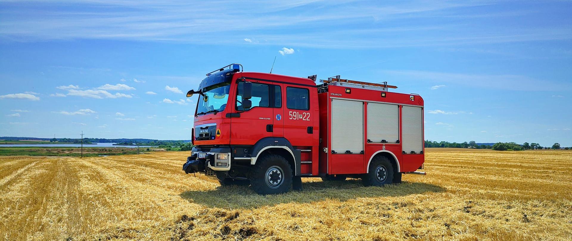 Czerwony samochód strażacki jest na ściernisku 