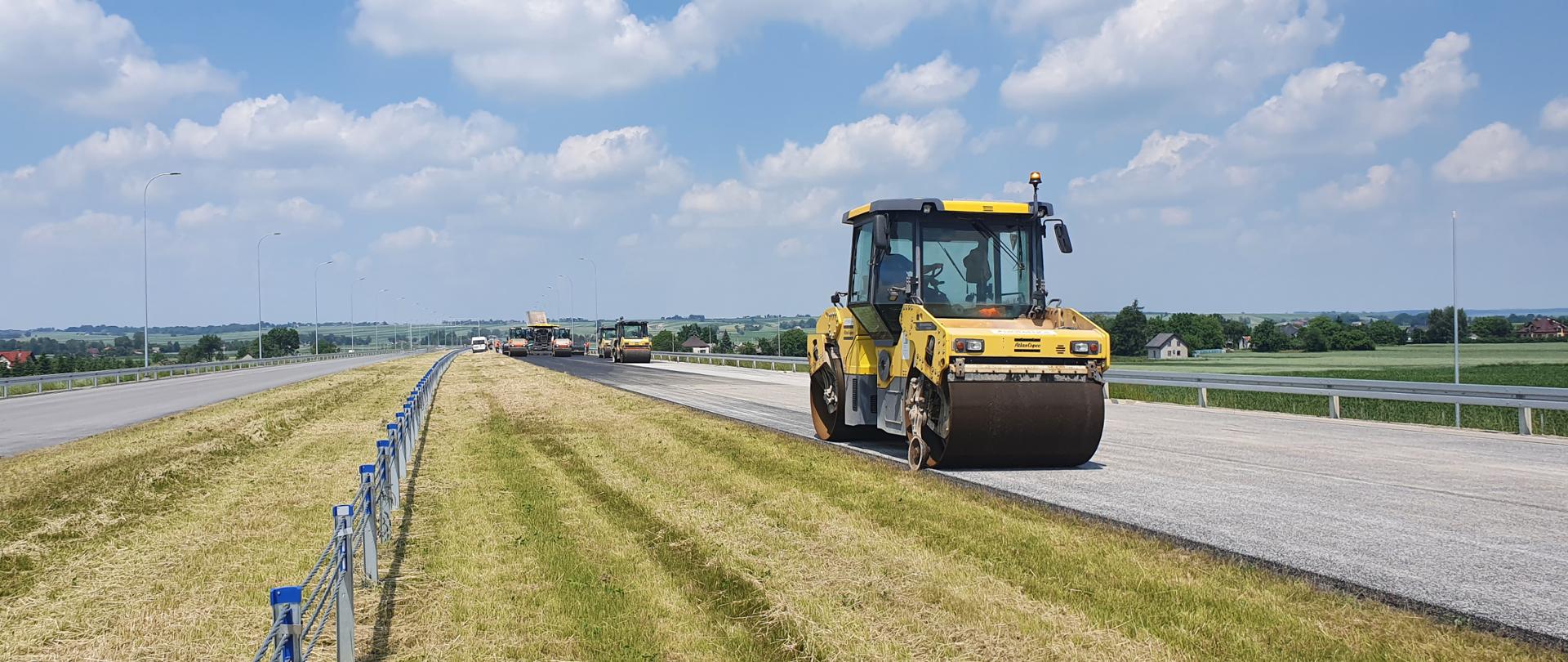 walec na pierwszym planie, na świeżo położonej masie, droga dwujezdniowa w budowie