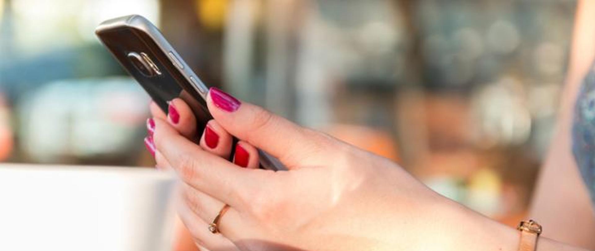 Dłonie trzymające telefon komórkowy