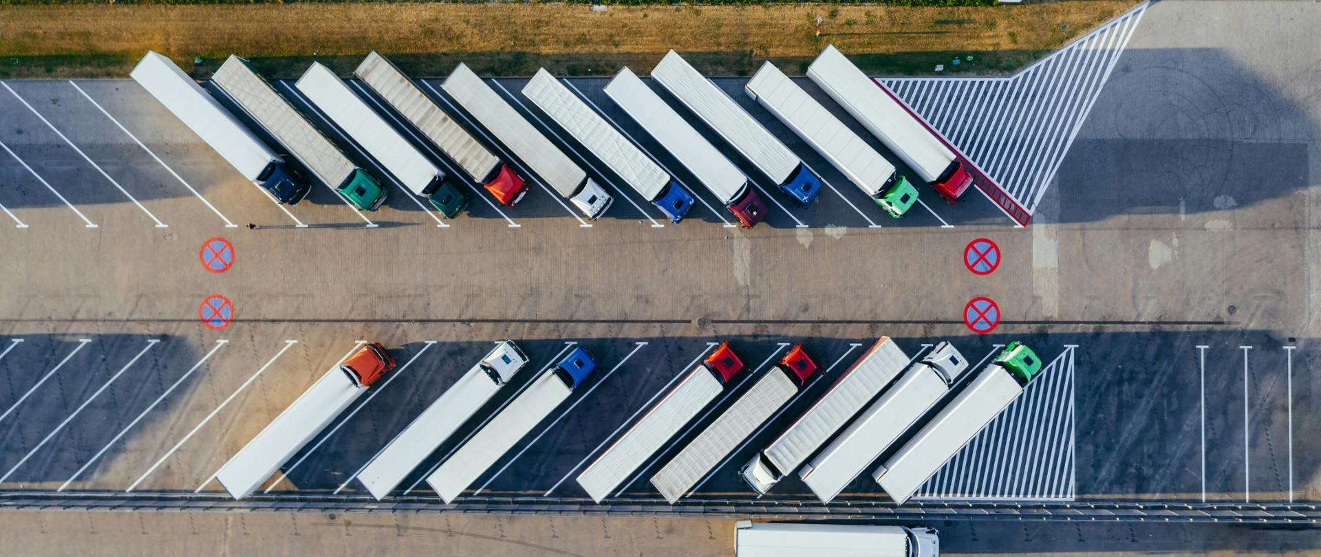 Widok z lotu ptaka na ciężarówki, które stoją na parkingu.
