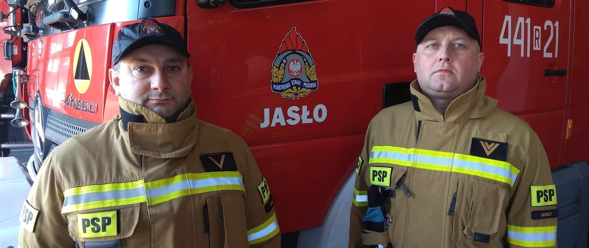 Na zdjęciu strażacy z JRG Jasło. Zdjęcie wykonano w garażu w KP PSP w Jaśle. Za strażakami czerwony samochód Mercedes Atego