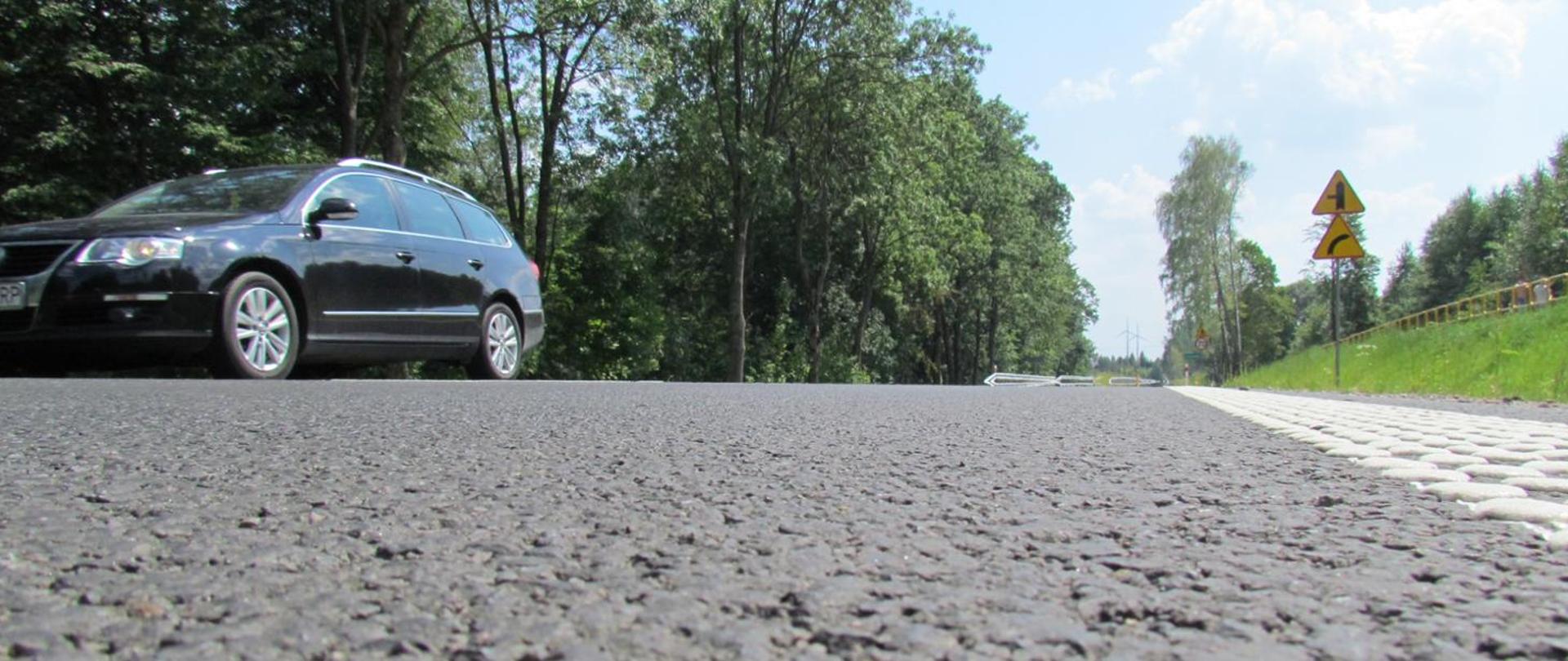 Nawierzchnia bitumiczna drogi, na której jedzie samochód osobowy