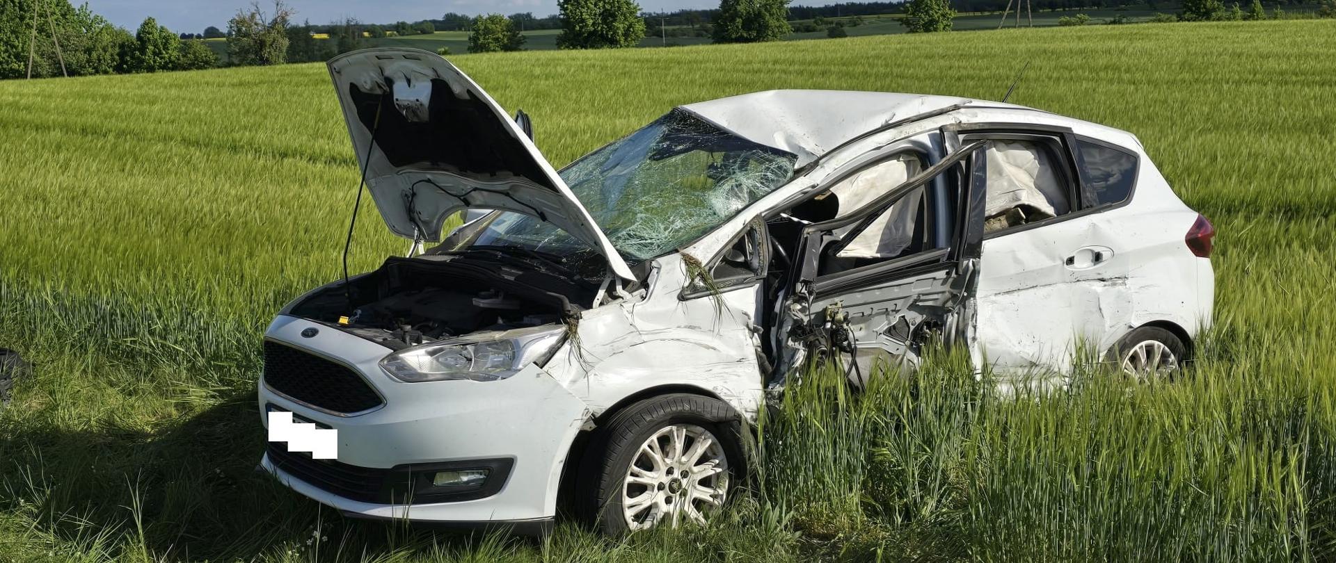 Mocno uszkodzony biały samochód na polu