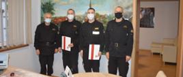 Awanse z okazji Narodowego Święta Niepodległości. Biuro zastępcy komendanta powiatowego PSP w Rawiczu. Na tle obrazu ściennego stoją awansowani strażacy w towarzystwie zastępcy komendanta powiatowego oraz zastępcy dowódcy JRG.