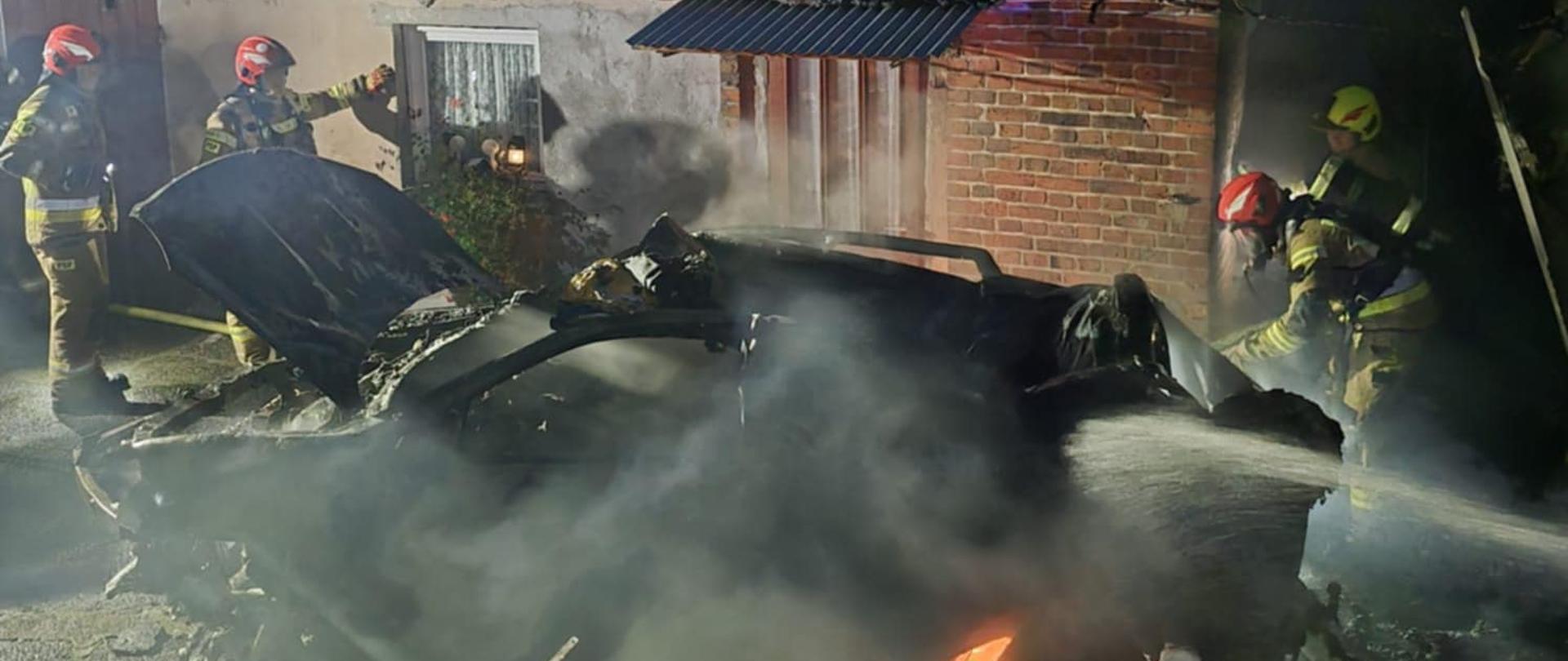 Grupa strażaków gasi pojazd