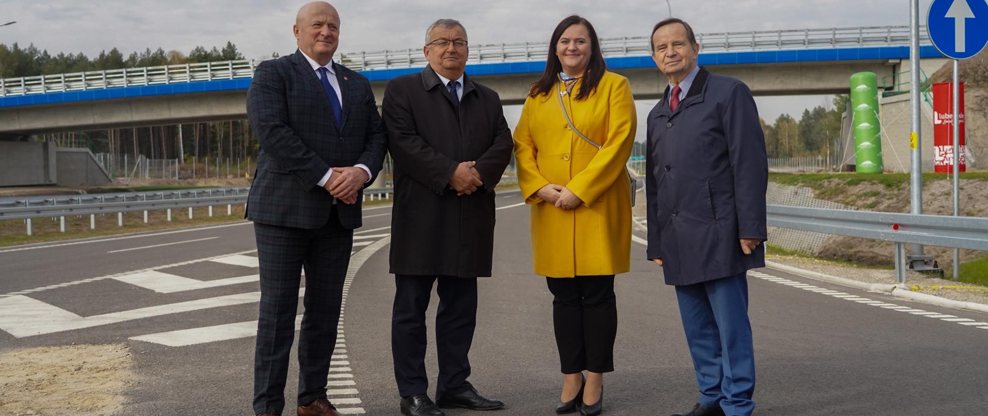 Na drodze w rzędzie stoją cztery osoby - trzech mężczyzn i wiceminister Małgorzata Jarosińska-Jedynak