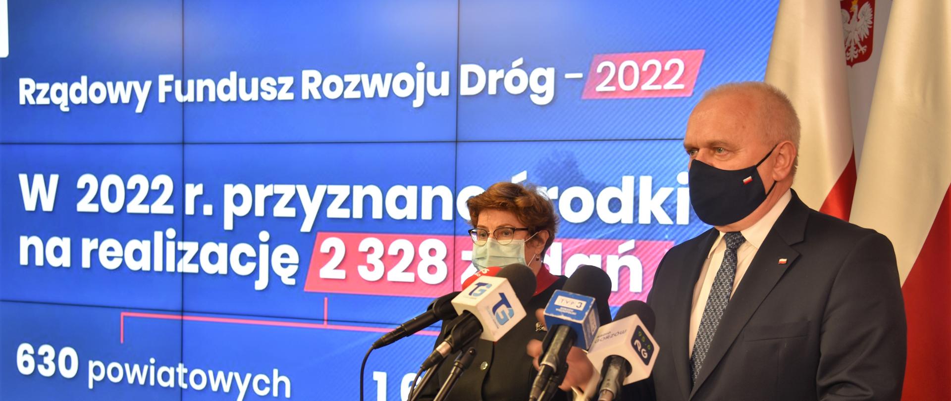 Wojewoda Lubuski przemawia w czasie konferencji. Obok poseł Elżbieta Płonka, w tle prezentacja wyników naboru programu Rządowego Funduszu Rozwoju Dróg w 2022 r