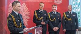 Na zdjęciu widoczny bryg. Maciej Wolański przemawiający z okazji przejścia na zaopatrzenie emerytalne, po prawej stojący kolejno bryg. Przemysław Przęczek Zastępca Małopolskiego Komendanta Wojewódzkiego PSP, st. bryg. Krzysztof Gładysz Komendant Miejski PSP w Tarnowie, bryg. Rafał Waśko Zastępca Komendanta Miejskiego PSP w Tarnowie.