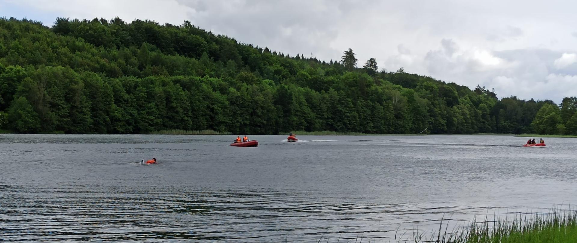 Na zdjęciu widzimy strażaków w łodziach podczas ćwiczeń na jeziorze oraz pozoranta udającego osobę poszkodowaną w wodzie