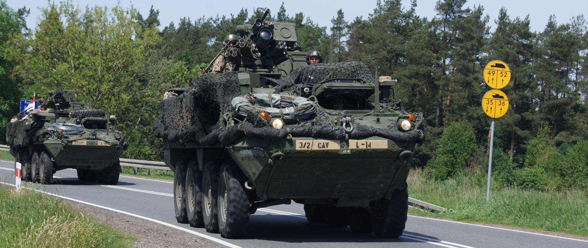 Przejazd kolumny wojskowej. Widoczne wozy bojowe w tle las.