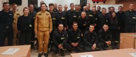 Widok z przodu. Zdjęcie grupowe. Po stronie lewej kadra KP PSP w Wadowicach, dalej uczestnicy szkolenia. W tle rozwinięty ekran projektora. 