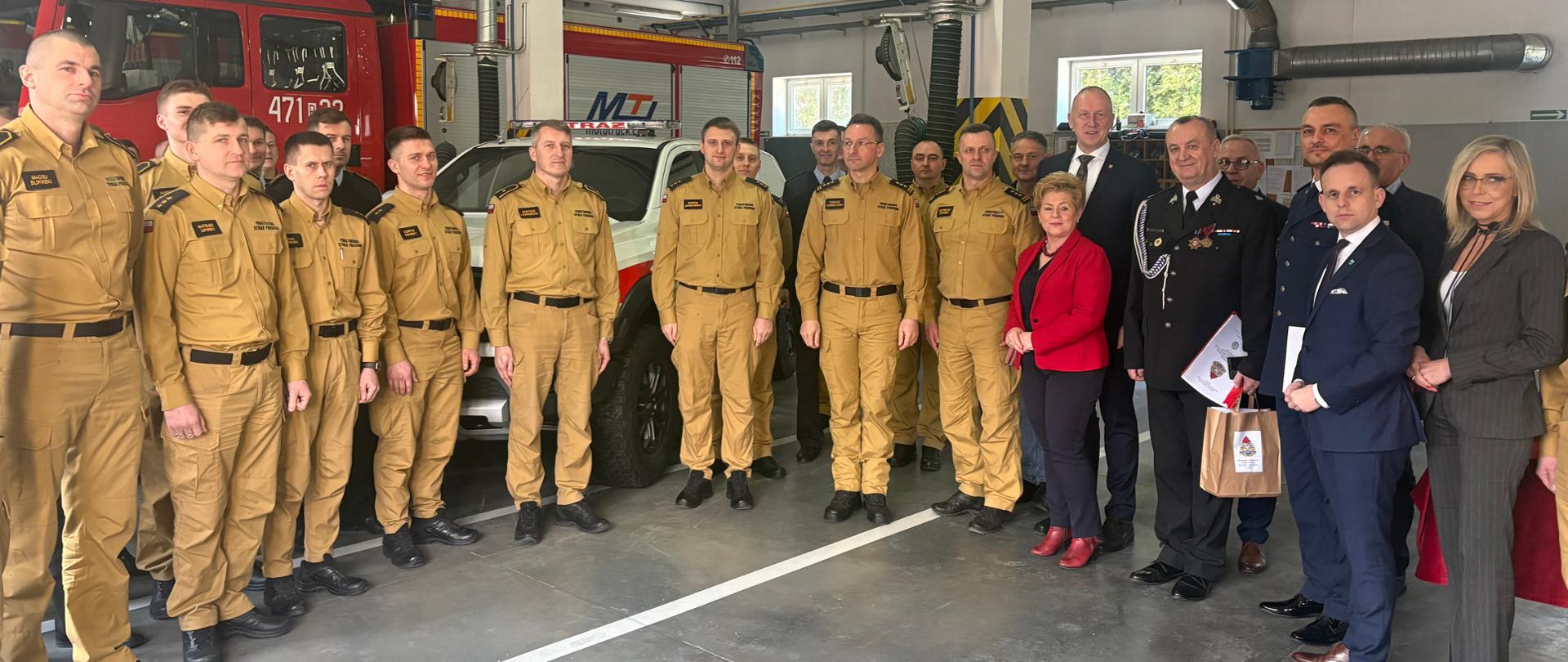 Zdjęcie przedstawia zaproszonych gości podczas zakończania odprawy rocznej w KP PSP w Kole na terenie garaży