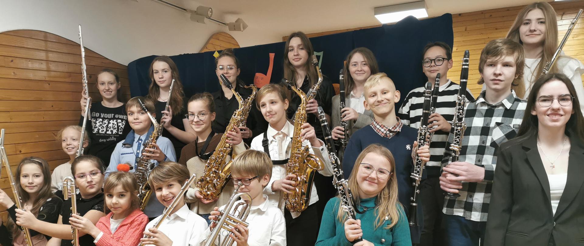 zdjęcie przedstawiające uczniów z instrumentami na scenie w szkolnej auli