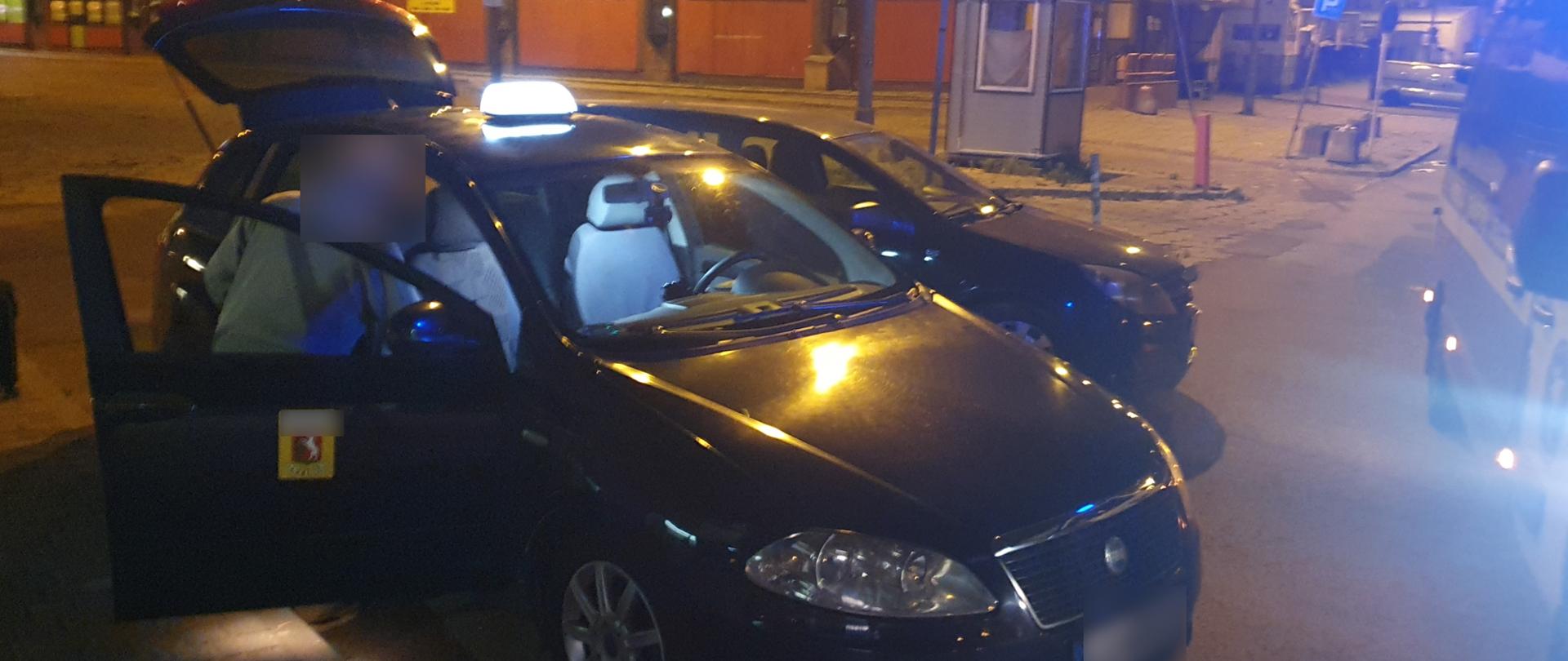 Mężczyzna stojący obok samochodu osobowego z kogutem TAXI