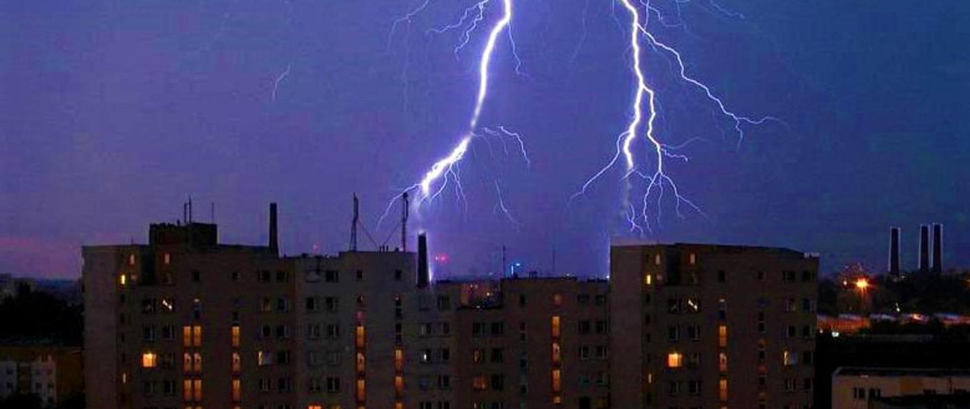 Zdjęcie przedstawia dwa pioruny nad wieżowcami.