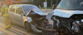 Zdjęcie obrazuje widok dwóch samochodów, które uległy zderzeniu. Zderzeniu uległ samochód osobowy marki Renault Scenic z samochodem dostawczym marki Peugeot Boxer. W tle zdjęcia widać dwa zespoły ratownictwa medycznego.