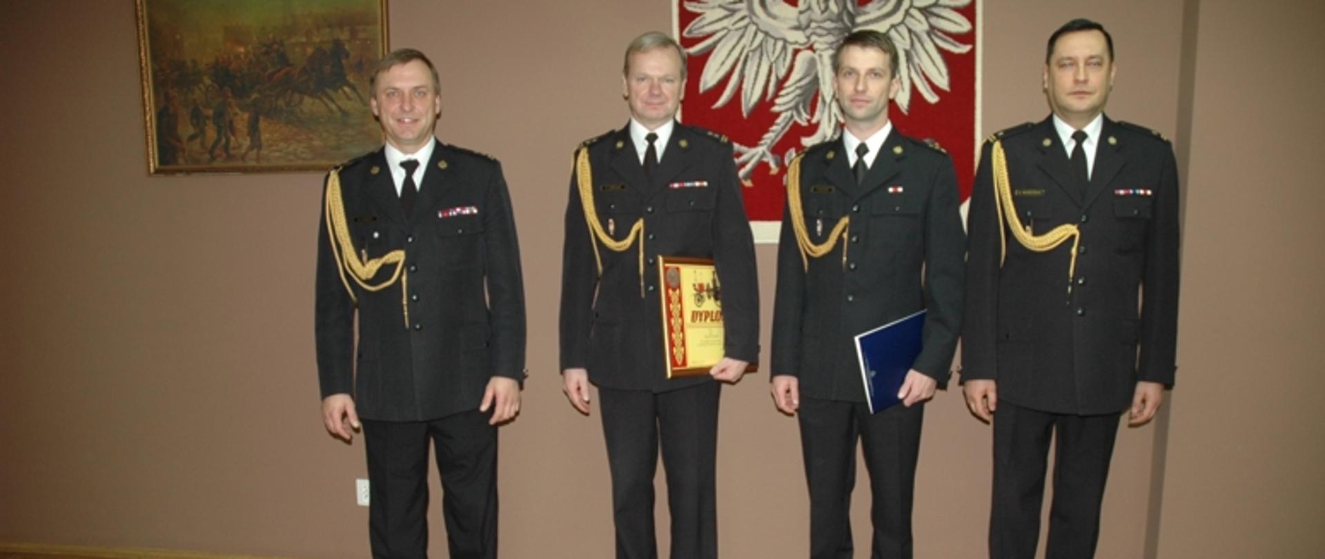 Ustawieni w szeregu, pozujący do zdjęcia w umundurowaniu wyjściowym: Komendant powiatowy PSP bryg. Robert Lebioda, dowódca JRG nr 1 w Stalowej Woli bryg. Krzysztof Cebulak, zastępca dowódcy zmiany I w JRG nr 2 w Stalowej Woli kpt. Grzegorz Olejarz, dowódca JRG nr 2 w Stalowej Woli mł. bryg. Marcin Wróblewski 