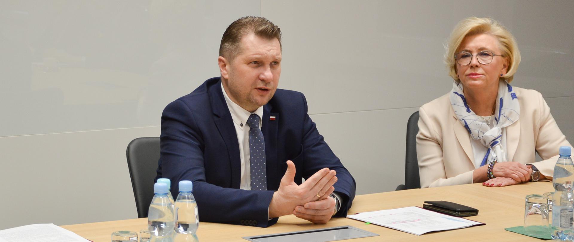 Minister Przemysław Czarnek oraz wiceminister Marzena Machałek siedzą przy stole podczas spotkania.