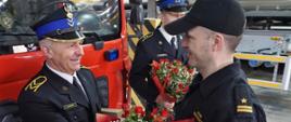 Dowódca wręcza kwiaty przechodzącemu na emeryturę strażakowi.